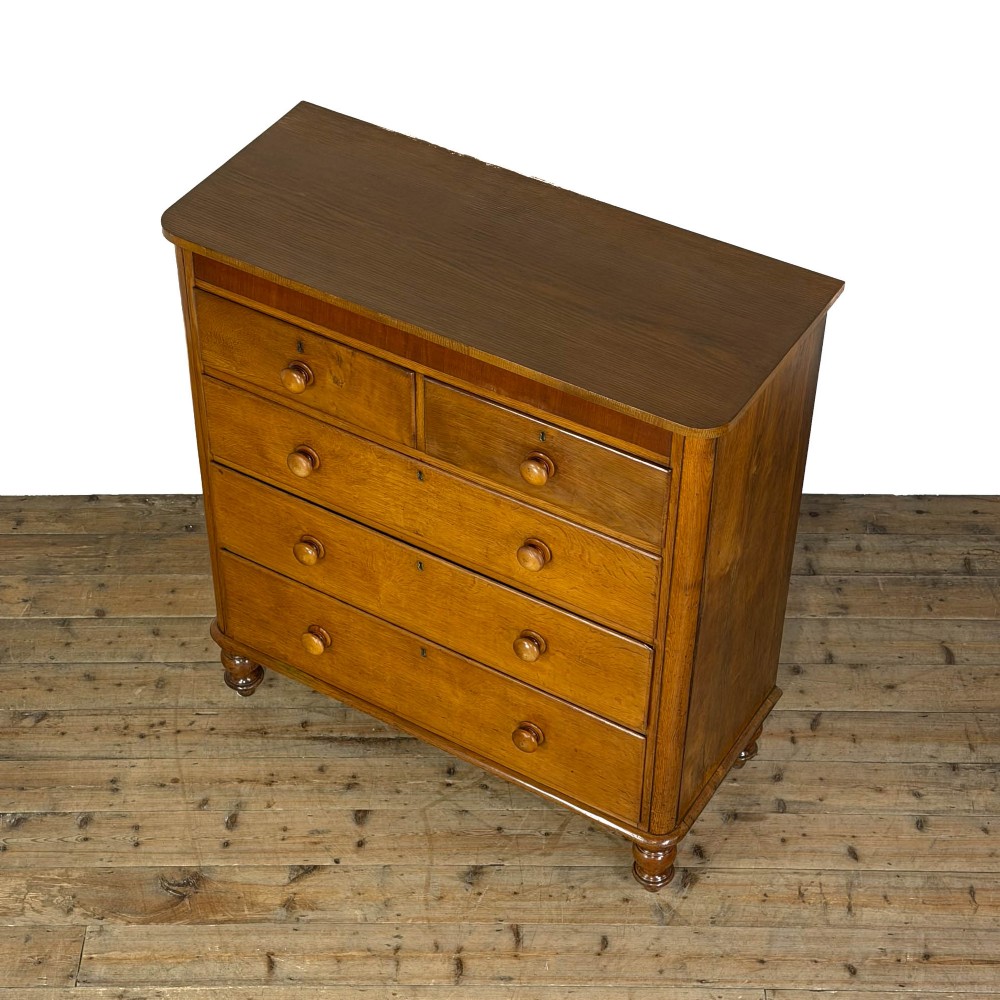A Victorian light oak chest of drawers featuring a two-over-three drawer configuration with turned wooden knobs and turned feet. View V