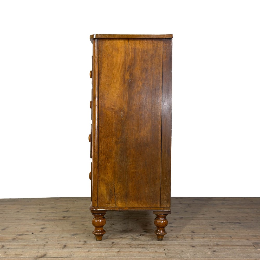 A Victorian light oak chest of drawers featuring a two-over-three drawer configuration with turned wooden knobs and turned feet. View VI