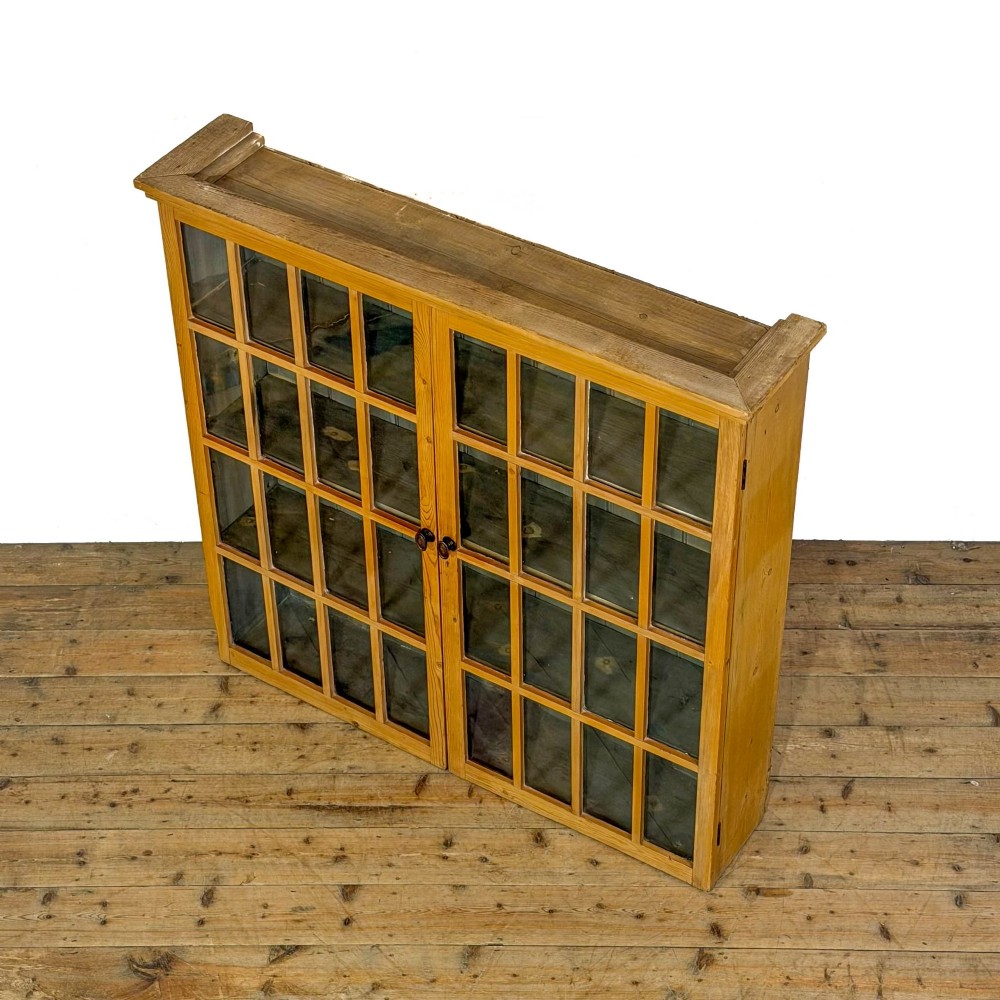 A large vintage pine cabinet featuring twin glazed doors with multiple glass panes and dark wooden knob handles. View VI