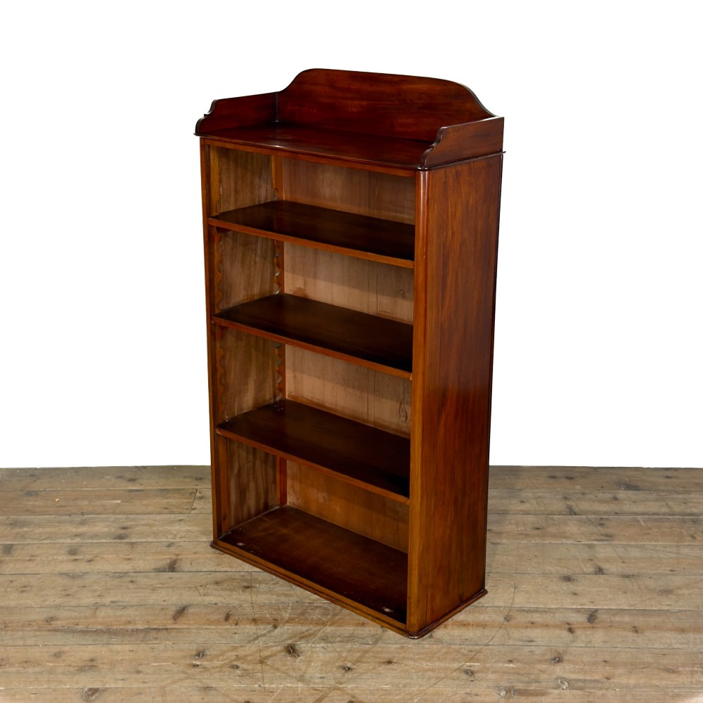 A small antique open mahogany bookcase featuring four tiers of shelving and a galleried top upstand.