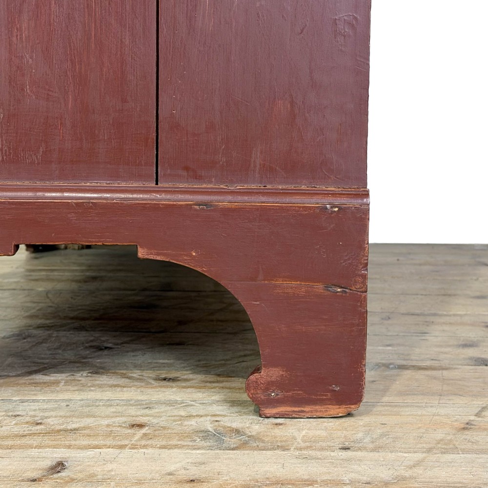 A tall Victorian painted pine housekeepers cupboard in a terracotta red finish, featuring a double-door upper cabinet over two short and two long drawers. View VII