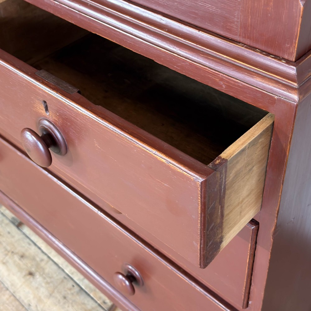A tall Victorian painted pine housekeepers cupboard in a terracotta red finish, featuring a double-door upper cabinet over two short and two long drawers. View VIII