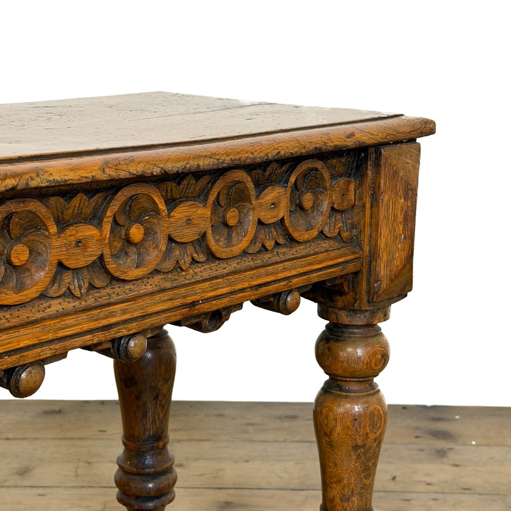 A long Victorian carved oak hall bench featuring a detailed floral rosette frieze, acorn drop pendants, and four turned legs on a light timber floor. View II