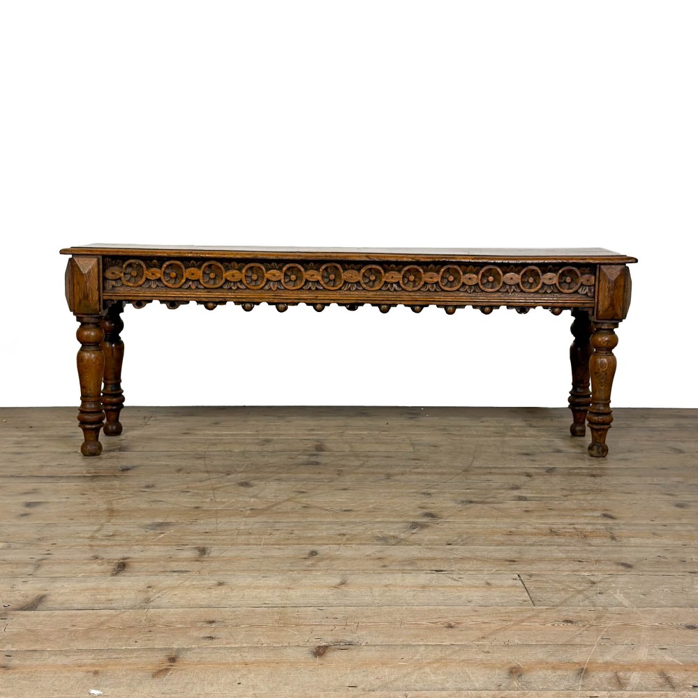 A long Victorian carved oak hall bench featuring a detailed floral rosette frieze, acorn drop pendants, and four turned legs on a light timber floor. View III