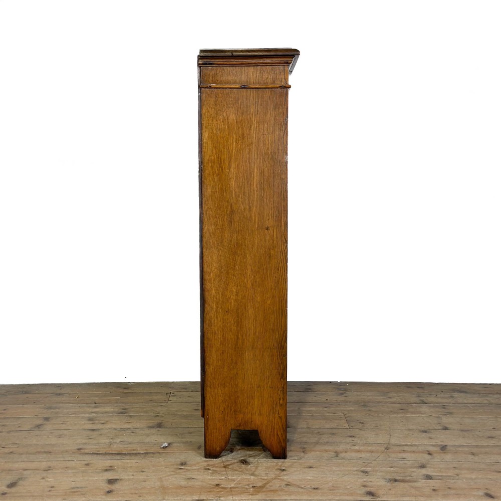 An open antique oak bookcase featuring four wooden shelves, a upper moulded cornice, vertical pine backboards, and shaped bracket feet. View II