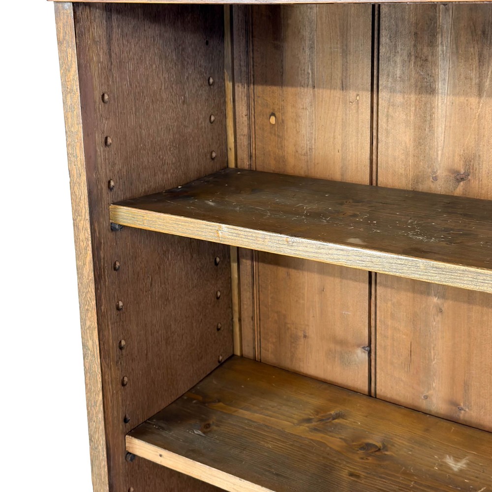 An open antique oak bookcase featuring four wooden shelves, a upper moulded cornice, vertical pine backboards, and shaped bracket feet. View III