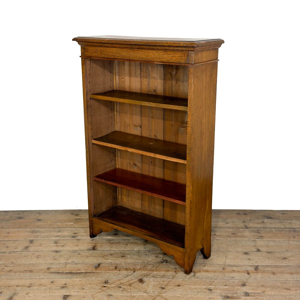 An open antique oak bookcase featuring four wooden shelves, a upper moulded cornice, vertical pine backboards, and shaped bracket feet. View IV