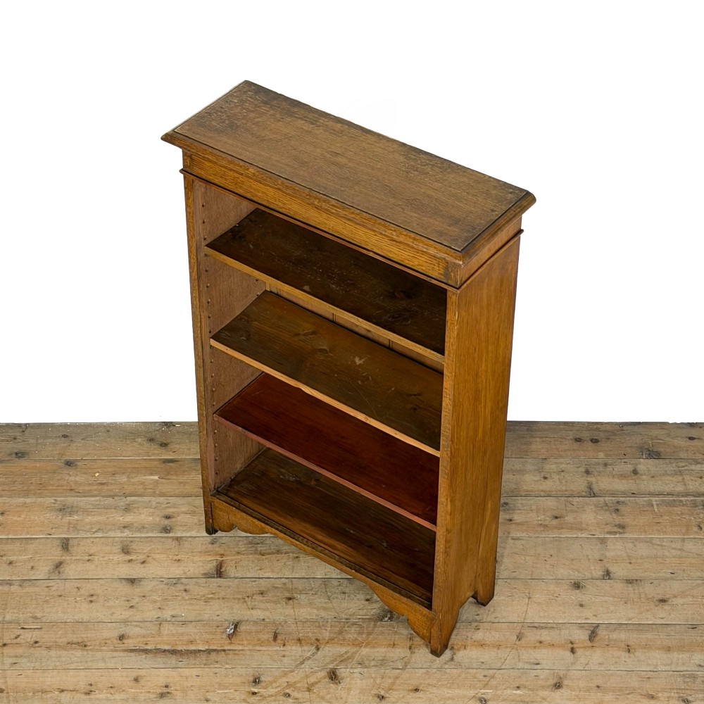 An open antique oak bookcase featuring four wooden shelves, a upper moulded cornice, vertical pine backboards, and shaped bracket feet. View V
