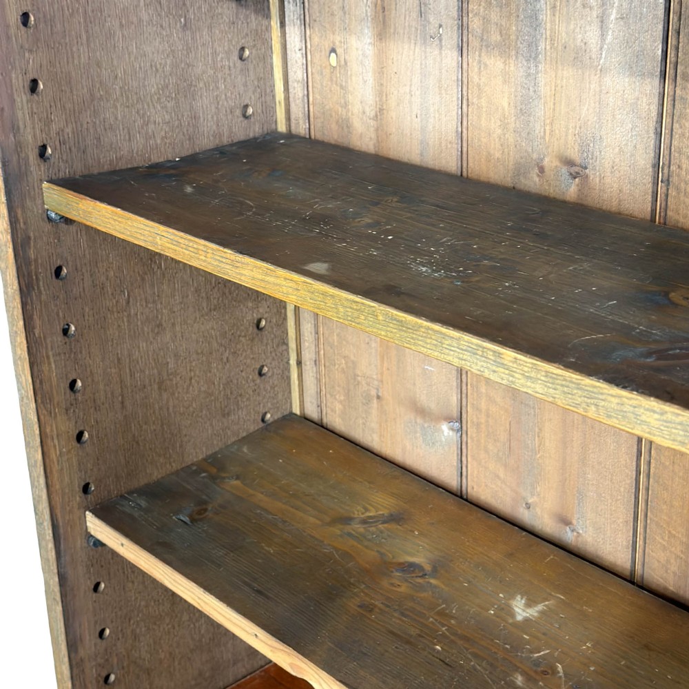 An open antique oak bookcase featuring four wooden shelves, a upper moulded cornice, vertical pine backboards, and shaped bracket feet. View VI