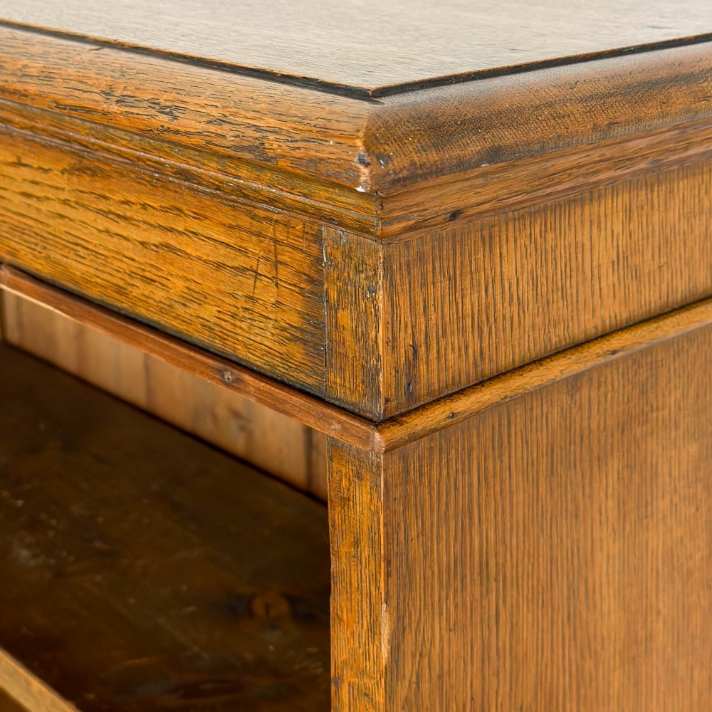 An open antique oak bookcase featuring four wooden shelves, a upper moulded cornice, vertical pine backboards, and shaped bracket feet. View VII