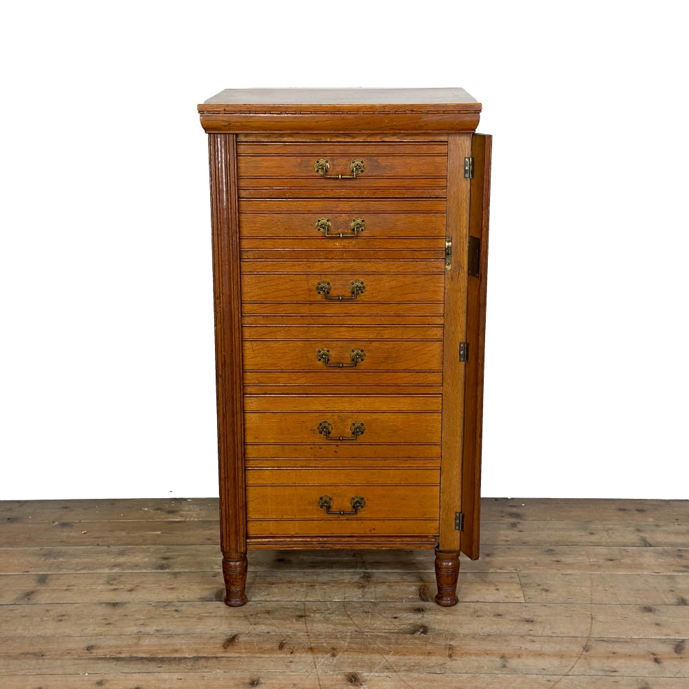 A tall late Victorian oak Wellington chest featuring seven drawers with brass drop handles, fluted side pilasters, and turned feet. View II