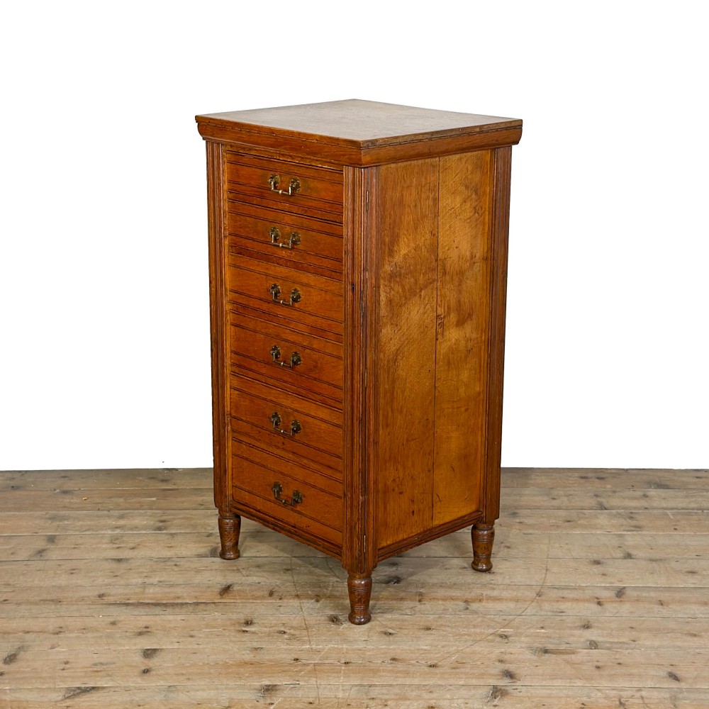 A tall late Victorian oak Wellington chest featuring seven drawers with brass drop handles, fluted side pilasters, and turned feet. View IV
