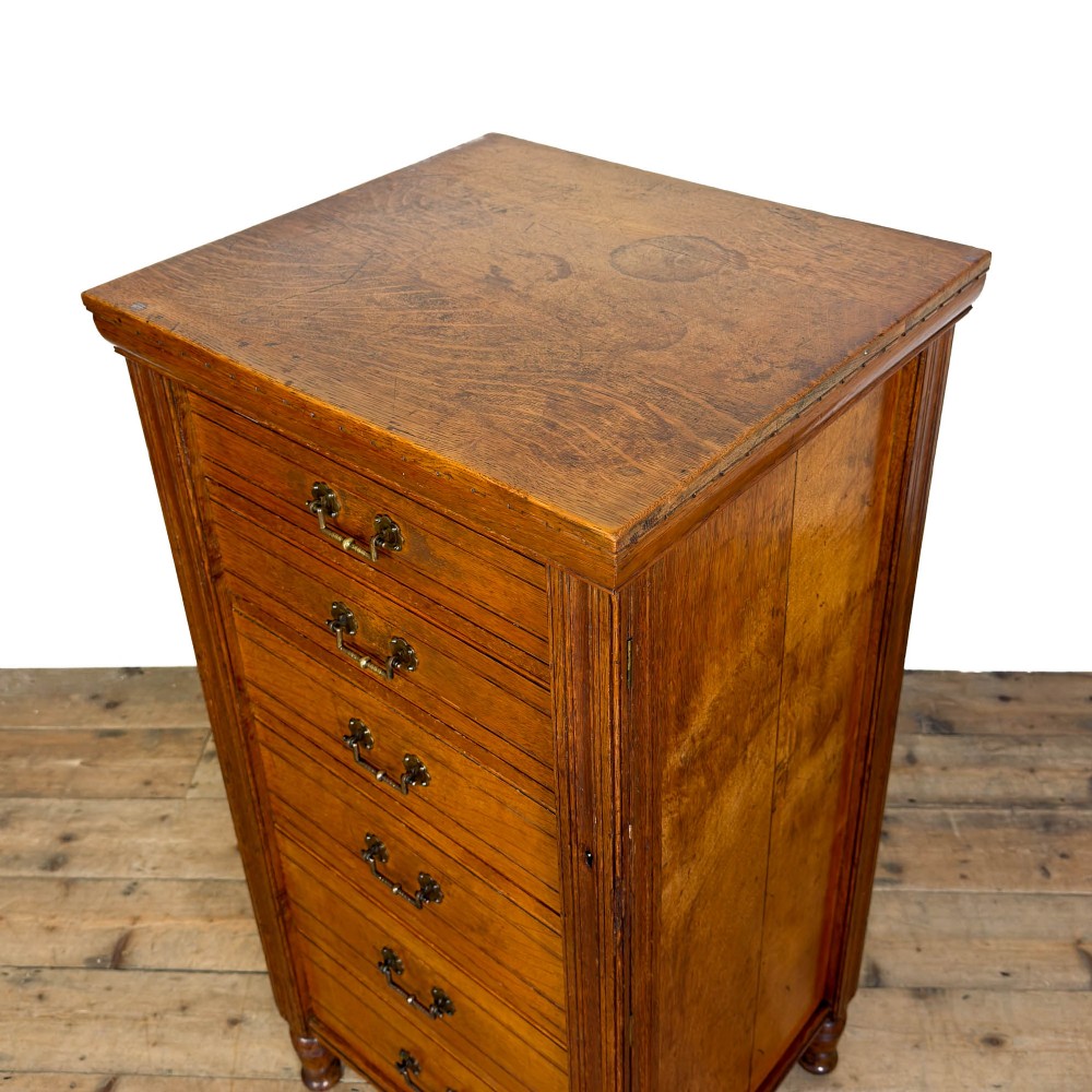 A tall late Victorian oak Wellington chest featuring seven drawers with brass drop handles, fluted side pilasters, and turned feet. View VII