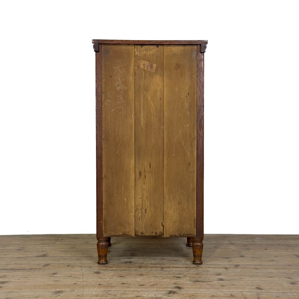 A tall late Victorian oak Wellington chest featuring seven drawers with brass drop handles, fluted side pilasters, and turned feet. View IX