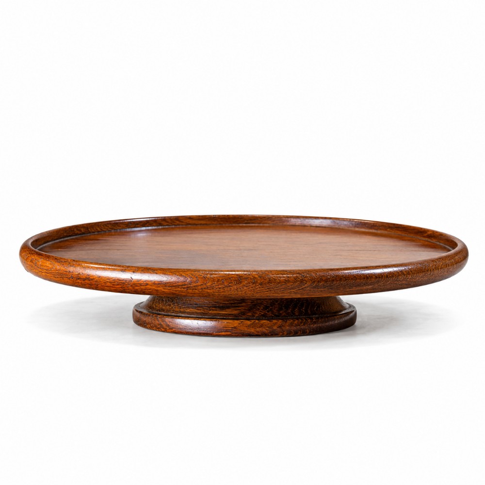 A circular dark oak revolving tray featuring a raised moulded lip and a broad pedestal base.