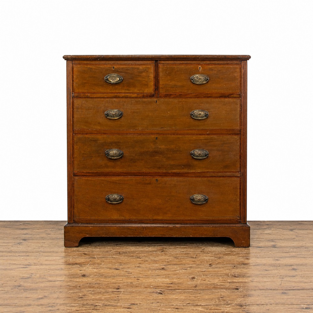 An Edwardian mahogany chest of drawers with two short over three long drawers, brass oval drop handles, and fine line inlay detail on a bracket base.