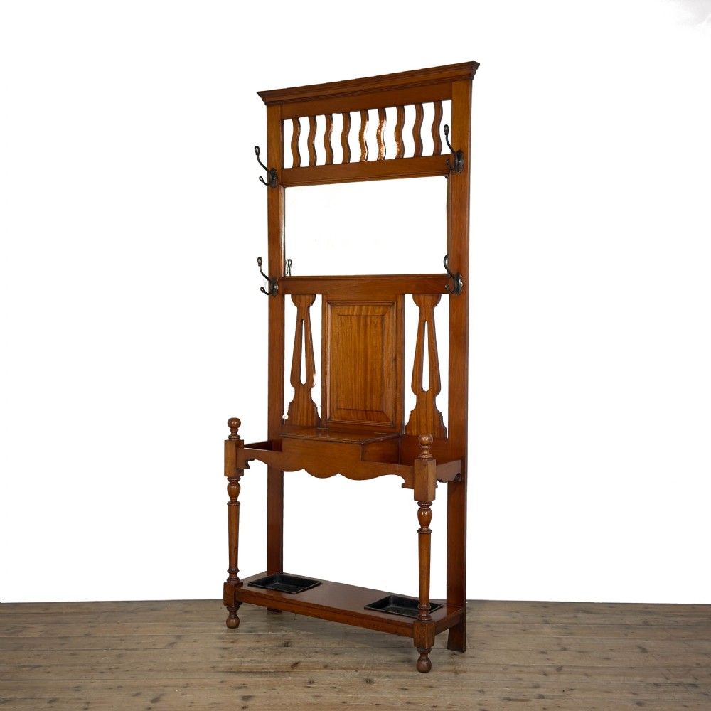 An antique Edwardian oak hall stand featuring a central mirror, hanging hooks, vertical spindle detailing, and a lower umbrella rack with drip trays. View II