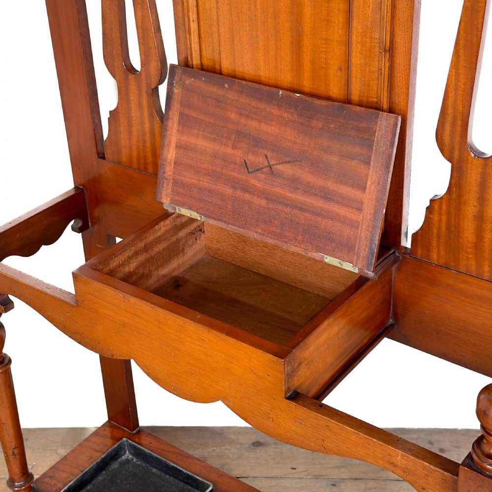 An antique Edwardian oak hall stand featuring a central mirror, hanging hooks, vertical spindle detailing, and a lower umbrella rack with drip trays. View IV