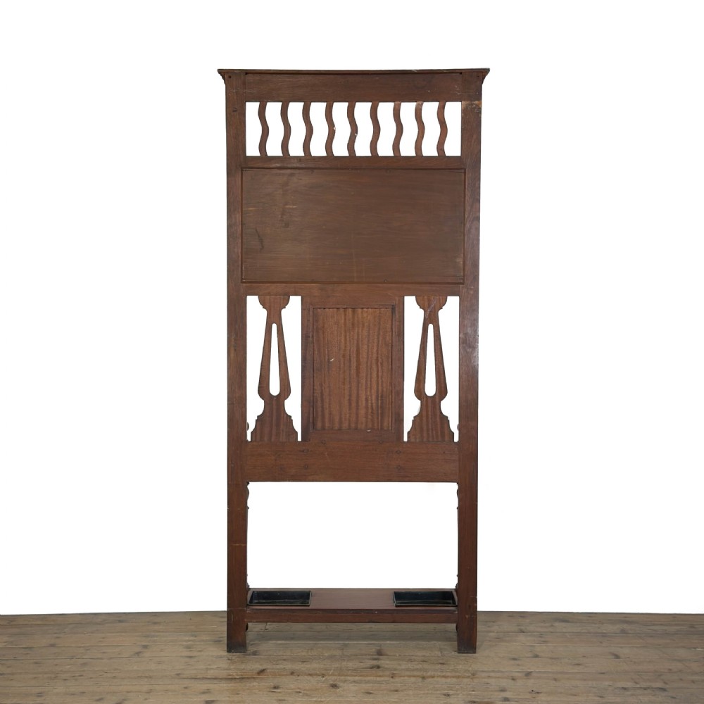 An antique Edwardian oak hall stand featuring a central mirror, hanging hooks, vertical spindle detailing, and a lower umbrella rack with drip trays. View VII