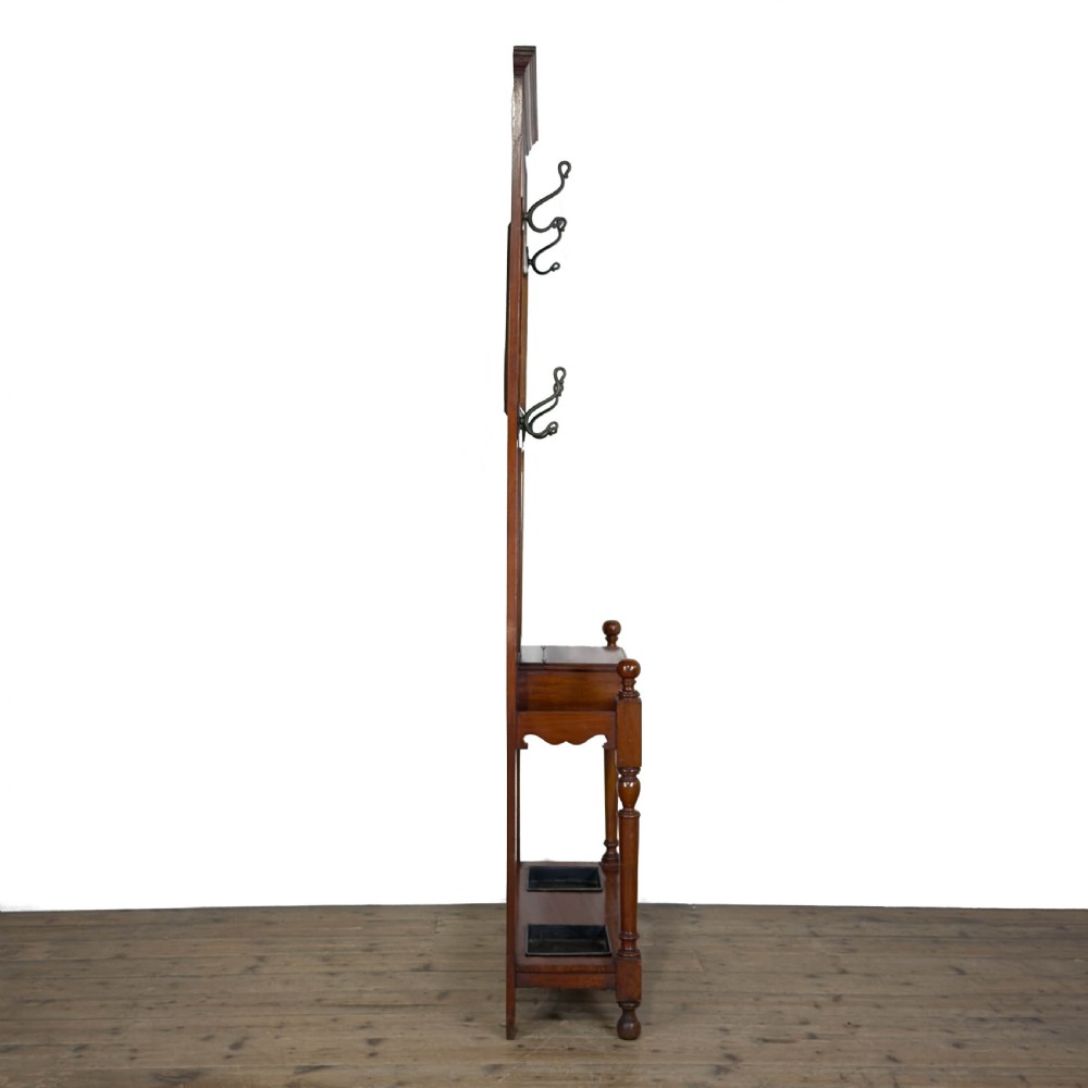 An antique Edwardian oak hall stand featuring a central mirror, hanging hooks, vertical spindle detailing, and a lower umbrella rack with drip trays. View VIII