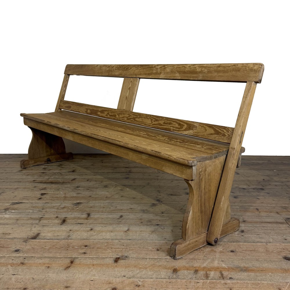 A long pine chapel bench featuring a reversible flip-over backrest and solid wooden side supports on a timber floor.