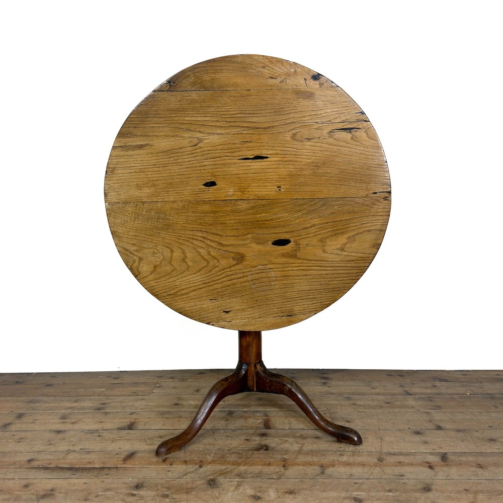 An antique Georgian light oak tilt-top table with a circular top supported by a central turned column and three splayed tripod legs.