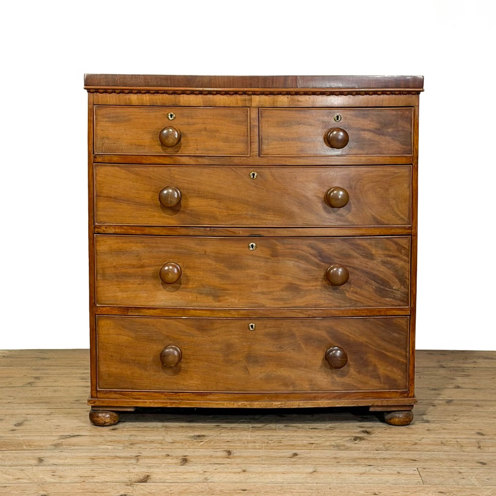 A nineteenth-century mahogany bow-front chest of drawers featuring two short over three long graduated drawers with turned knob handles.