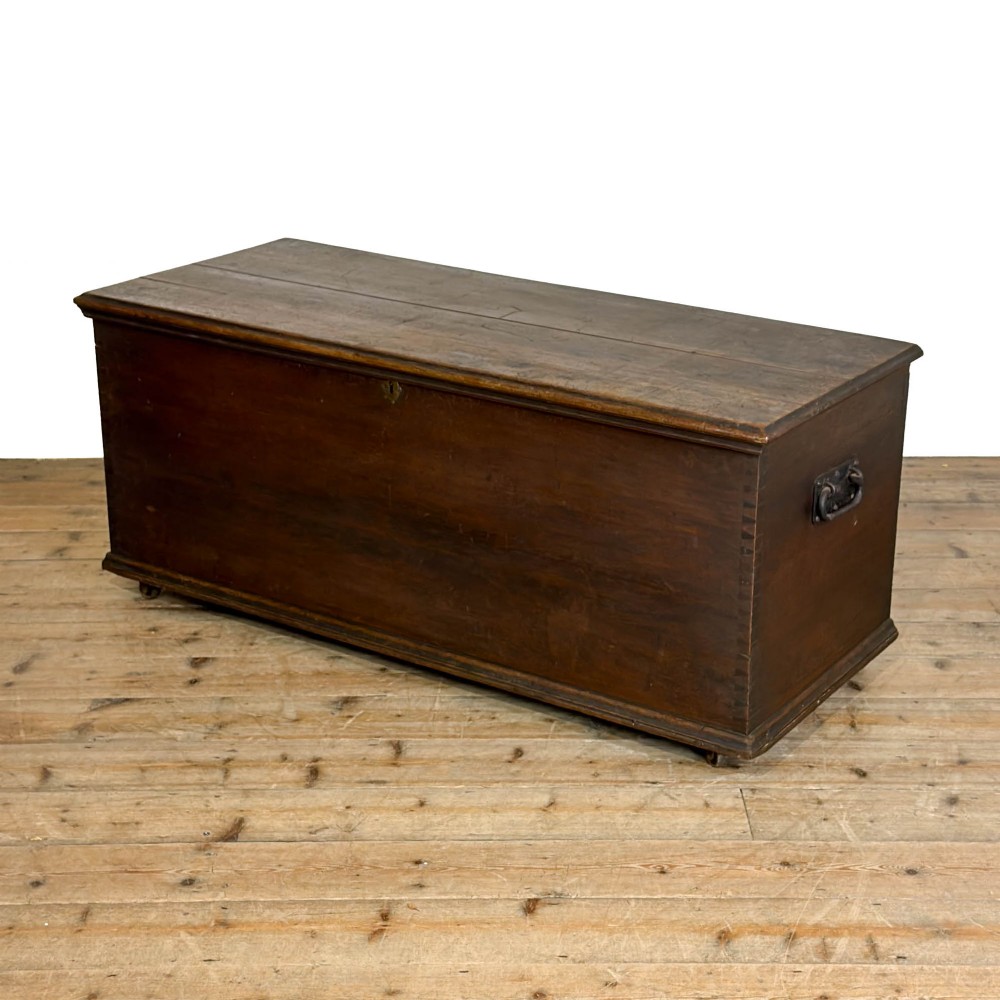 A large dark brown oak blanket box featuring a flat hinged lid, visible dovetail joinery, side drop handles, and a central keyhole.