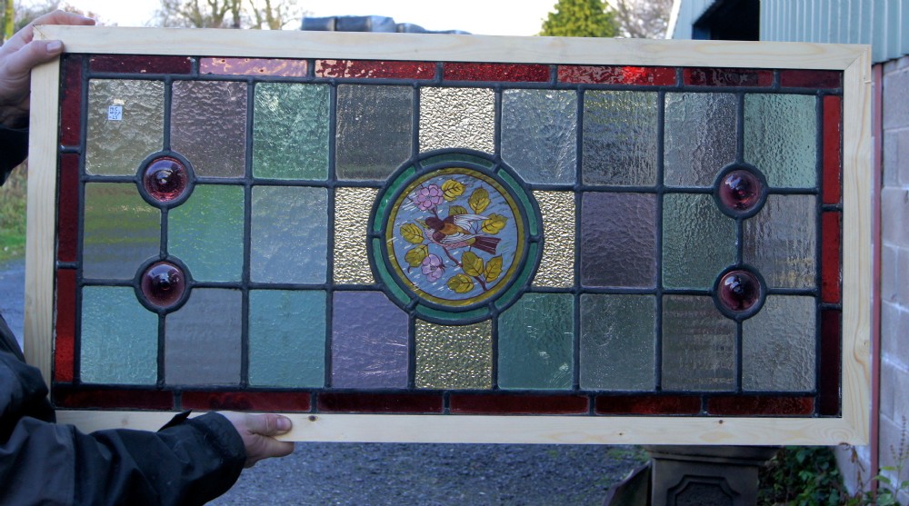A large horizontal Victorian painted stained glass bird window 
