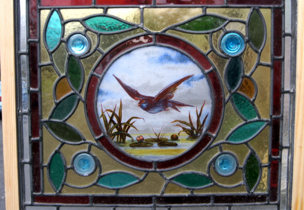 A stunning stained glass window with a painted bird centre