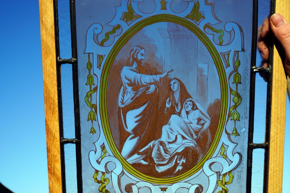 An antique rectangular stained glass panel featuring a central oval medallion with a hand-painted biblical scene surrounded by scrollwork in blue and yellow accents. View II