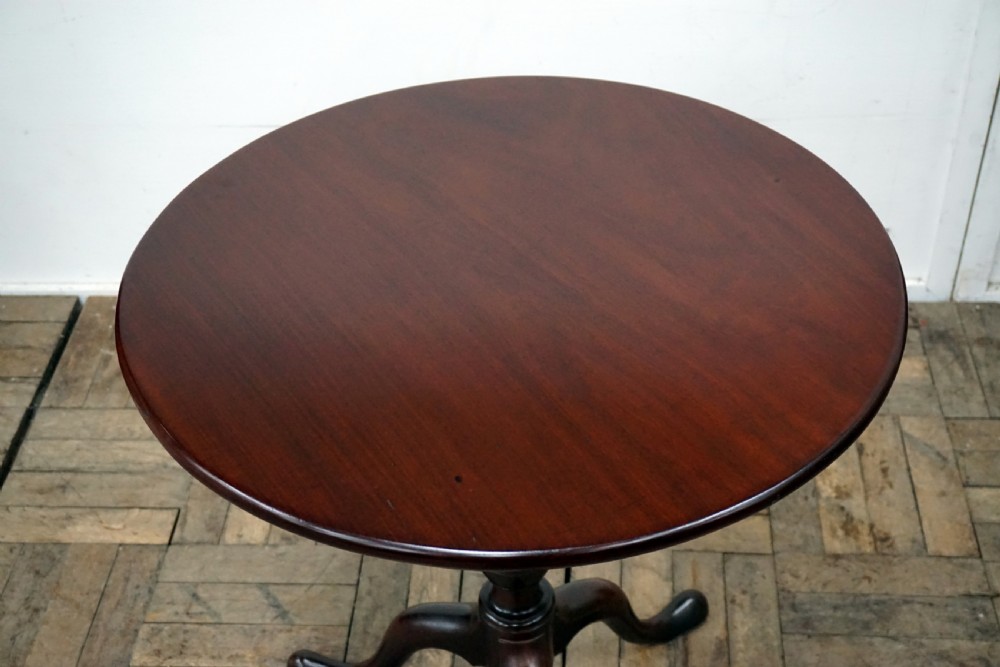 A Georgian mahogany tilt-top table featuring a circular top over a turned central stem and tripod cabriole legs with pad feet. View II