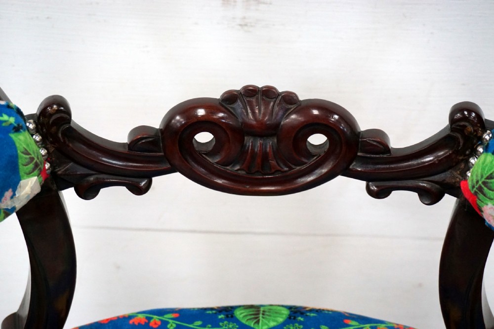 A Victorian mahogany armchair with carved scrollwork, padded armrests, cabriole legs, and vibrant blue upholstery featuring botanical floral and dragonfly patterns. View VI