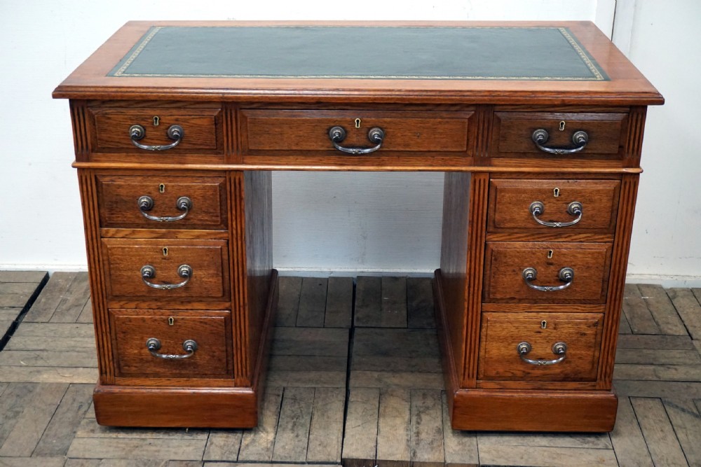 A small clean oak pedastal desk with 9 drawers