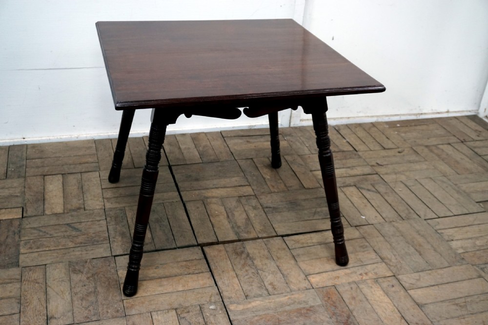 A square dark walnut coffee table featuring ring-turned legs and a shaped apron underneath.
