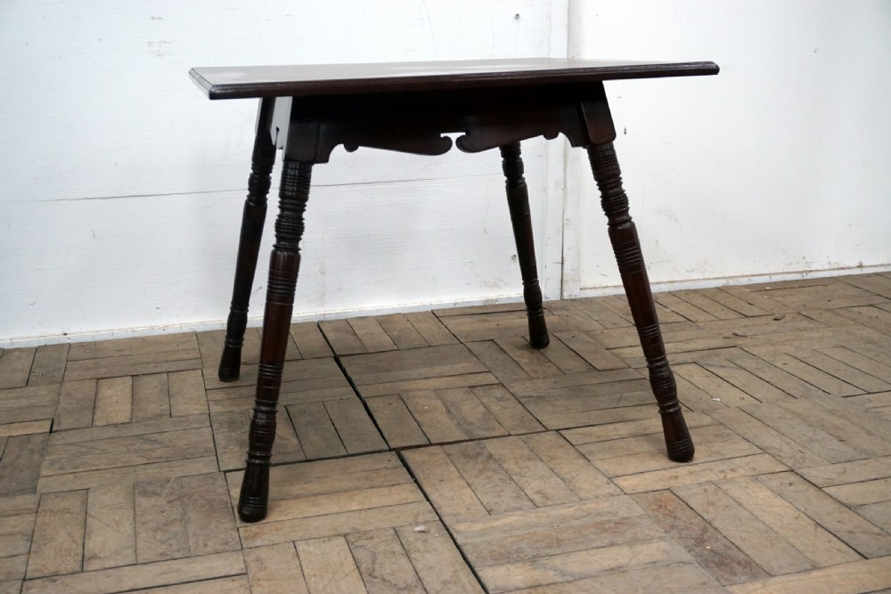A square dark walnut coffee table featuring ring-turned legs and a shaped apron underneath. View II