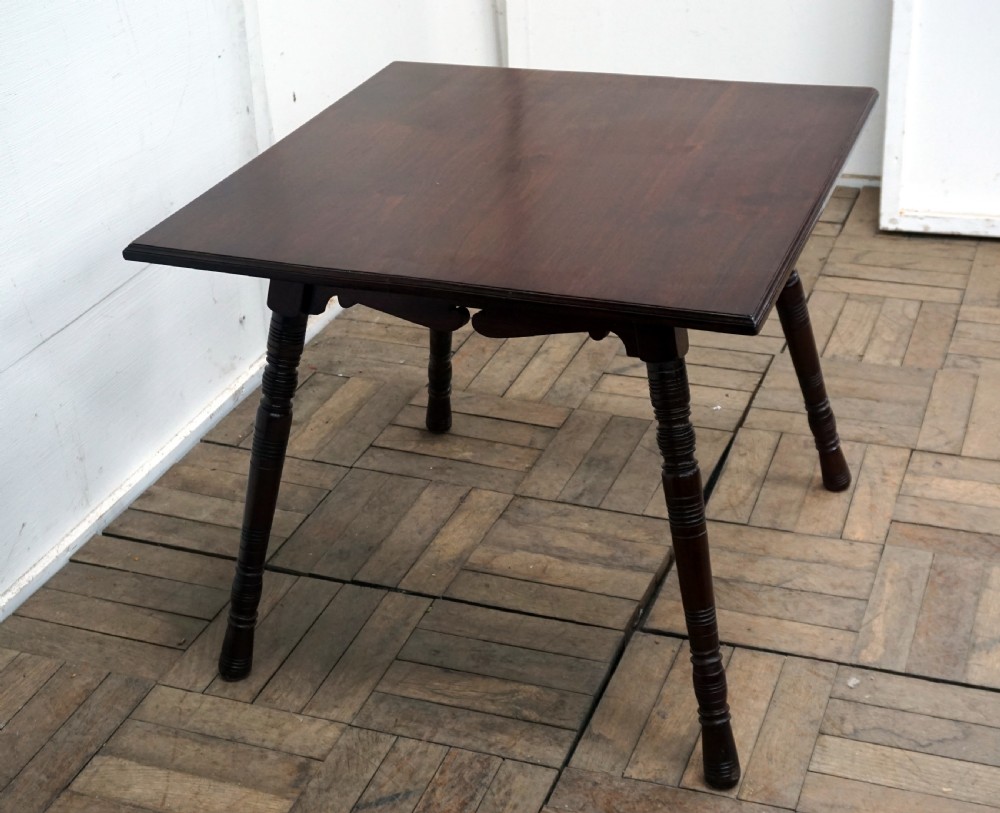 A square dark walnut coffee table featuring ring-turned legs and a shaped apron underneath. View III
