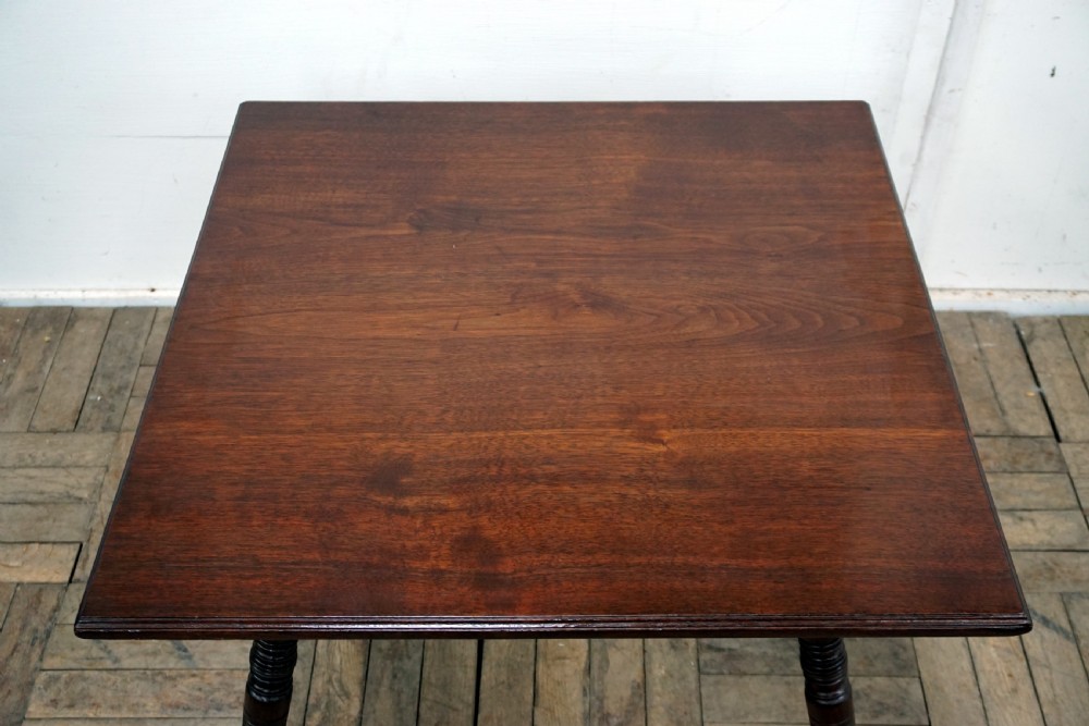A square dark walnut coffee table featuring ring-turned legs and a shaped apron underneath. View IV