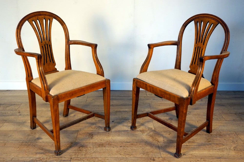 A pair of wooden armchairs crafted from birch and elm with slotted back splats and light beige upholstered seats.