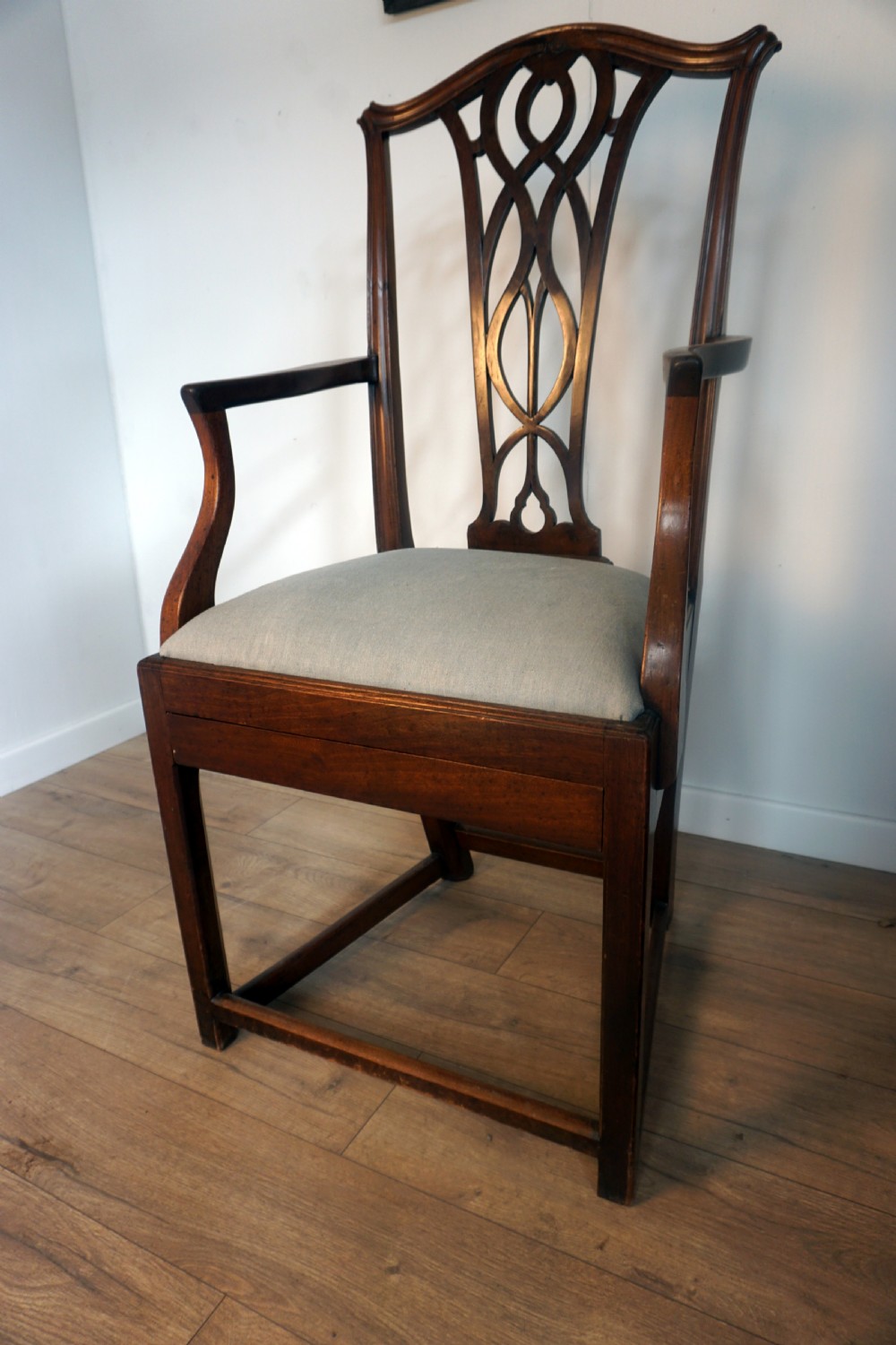 A late Georgian dark mahogany carver armchair featuring a carved pierced splat back, shaped arms, and a light grey drop-in upholstered seat. View II
