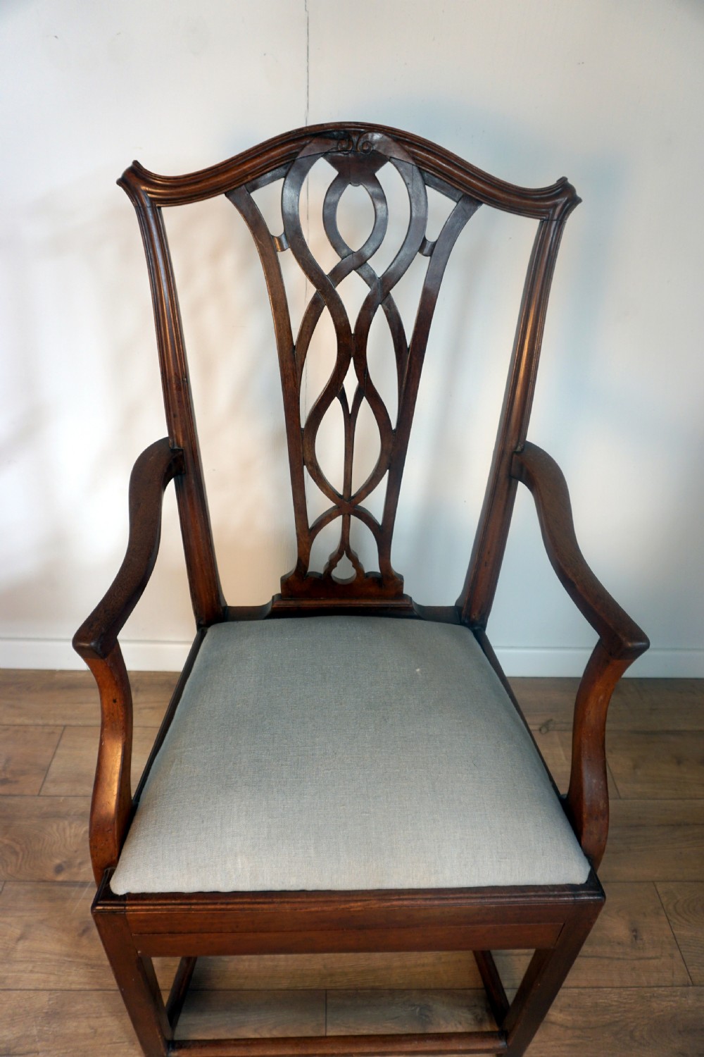 A late Georgian dark mahogany carver armchair featuring a carved pierced splat back, shaped arms, and a light grey drop-in upholstered seat. View III