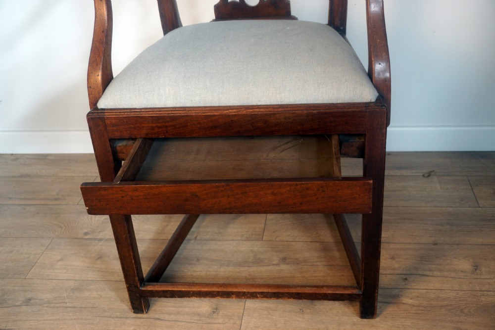 A late Georgian dark mahogany carver armchair featuring a carved pierced splat back, shaped arms, and a light grey drop-in upholstered seat. View IV