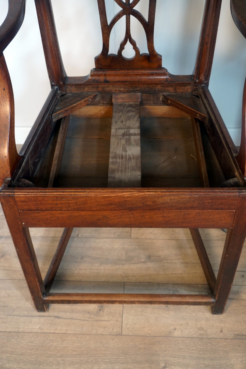 A late Georgian dark mahogany carver armchair featuring a carved pierced splat back, shaped arms, and a light grey drop-in upholstered seat. View VII