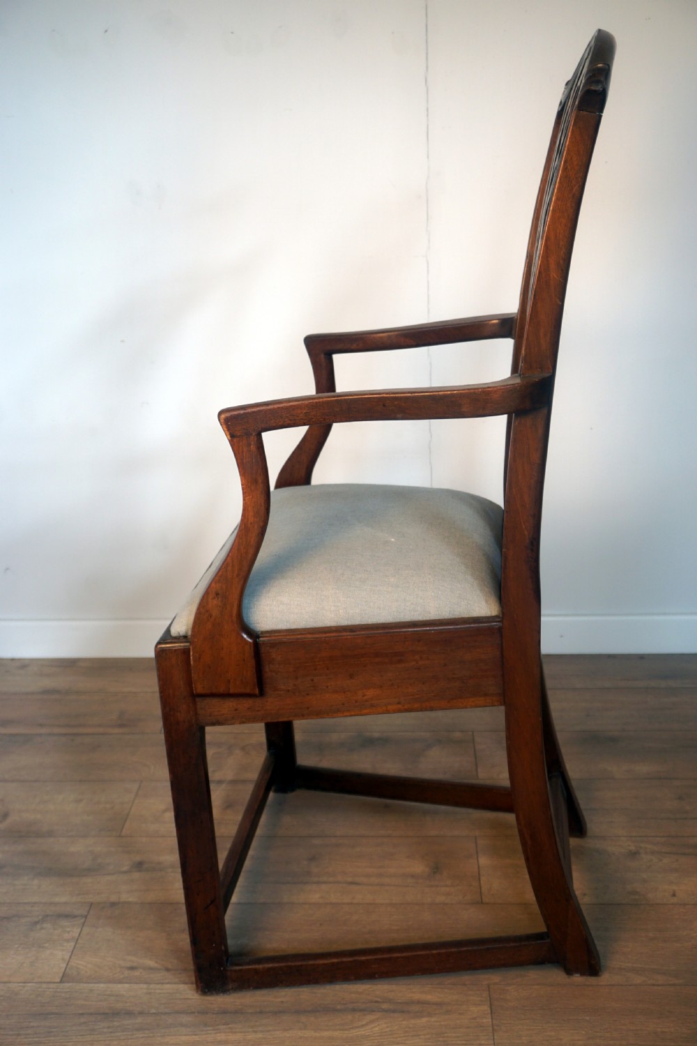 A late Georgian dark mahogany carver armchair featuring a carved pierced splat back, shaped arms, and a light grey drop-in upholstered seat. View VIII