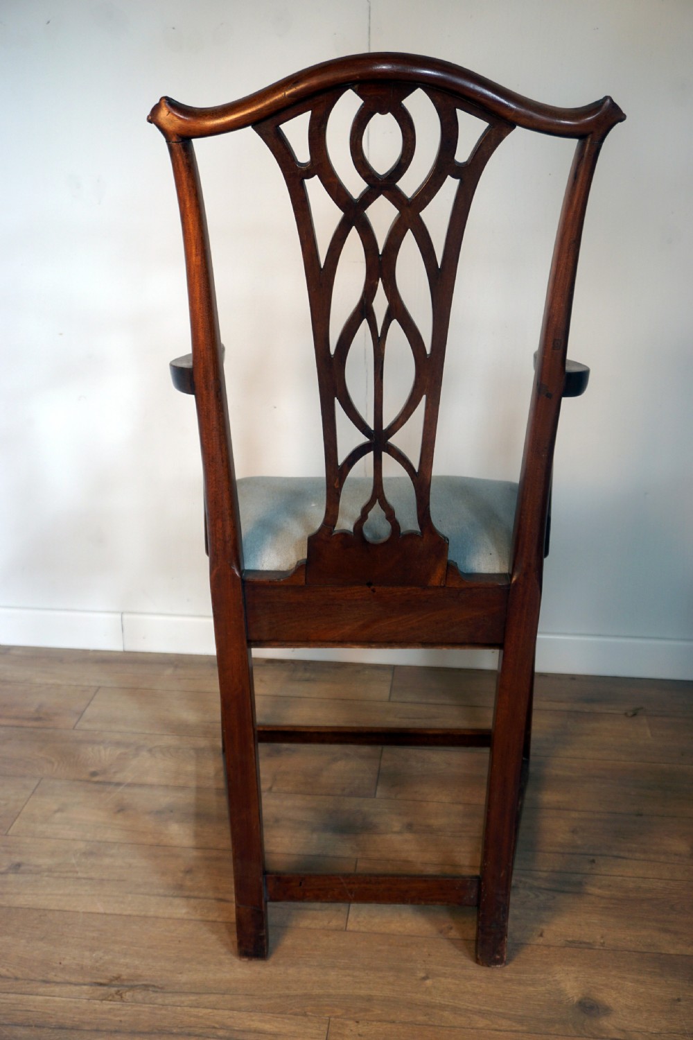 A late Georgian dark mahogany carver armchair featuring a carved pierced splat back, shaped arms, and a light grey drop-in upholstered seat. View IX