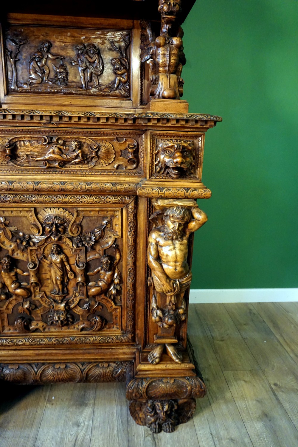 A two-tier carved wooden buffet featuring detailed relief panels of mythological scenes, carved putti, and supporting caryatid figures. View II