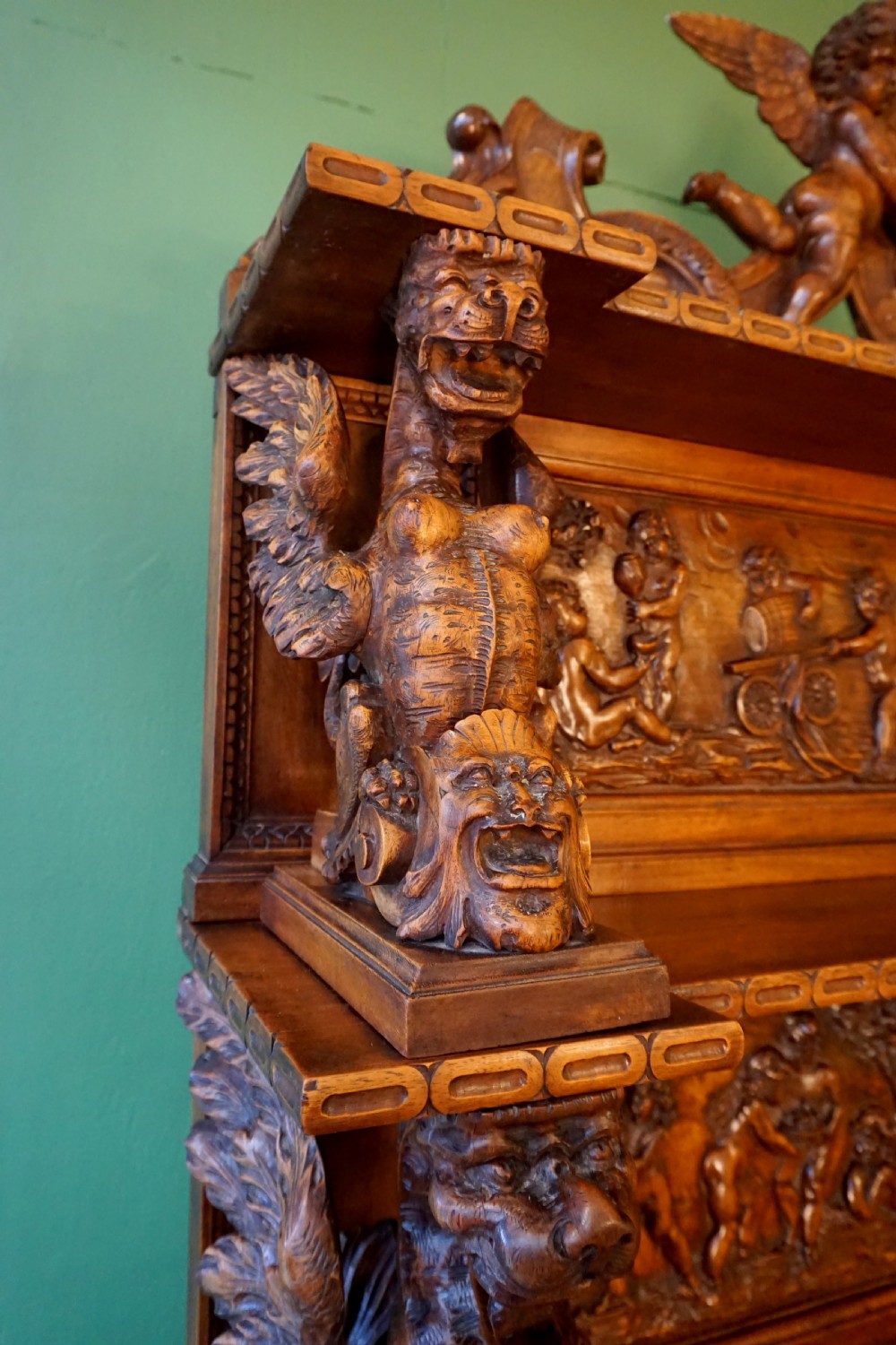 A two-tier carved wooden buffet featuring detailed relief panels of mythological scenes, carved putti, and supporting caryatid figures. View IV