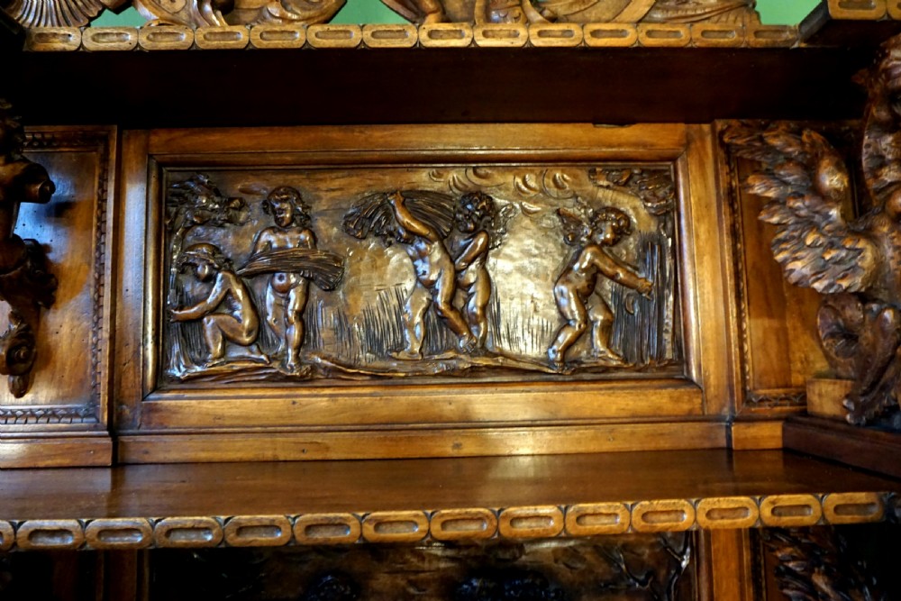 A two-tier carved wooden buffet featuring detailed relief panels of mythological scenes, carved putti, and supporting caryatid figures. View VIII