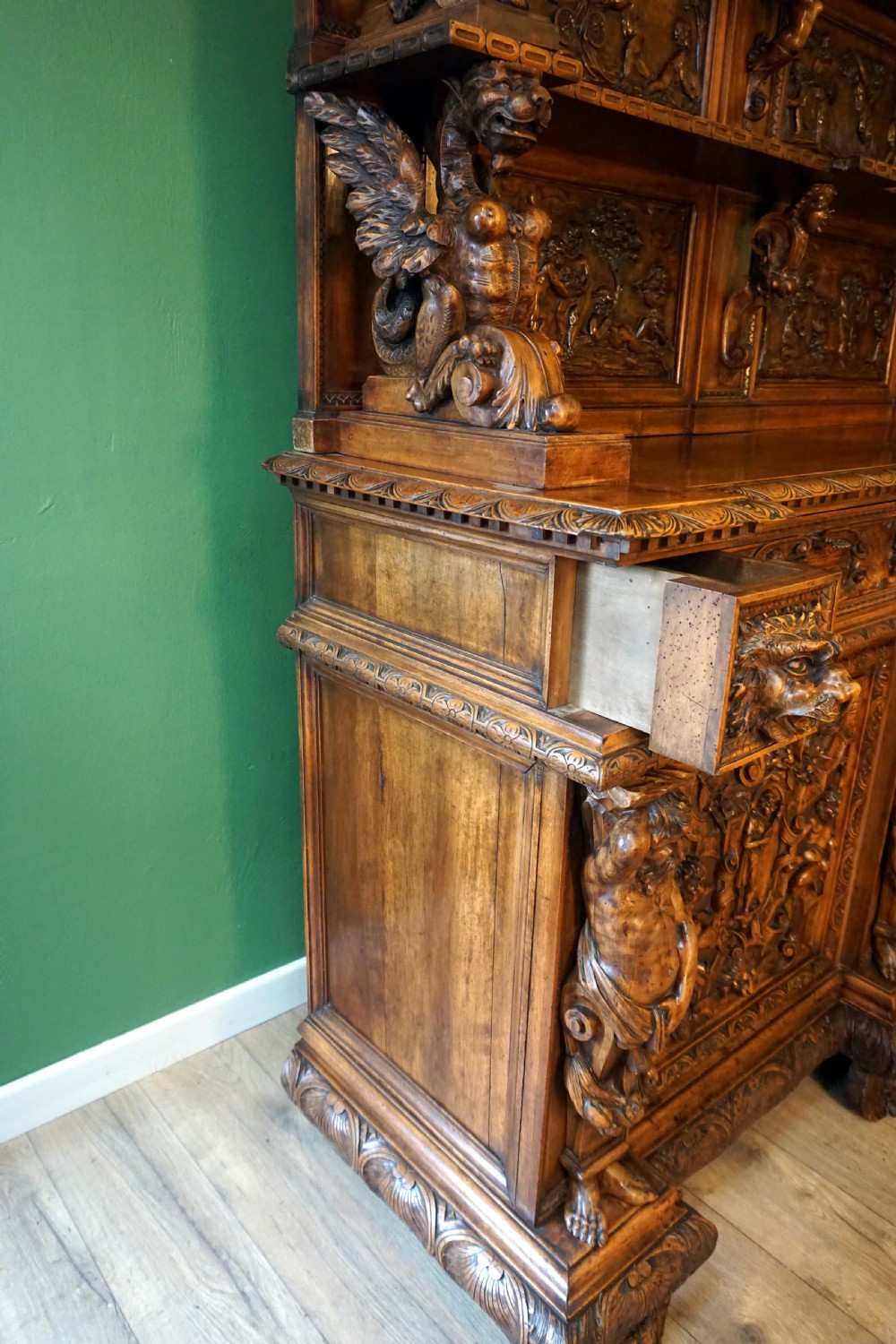 A two-tier carved wooden buffet featuring detailed relief panels of mythological scenes, carved putti, and supporting caryatid figures. View XII