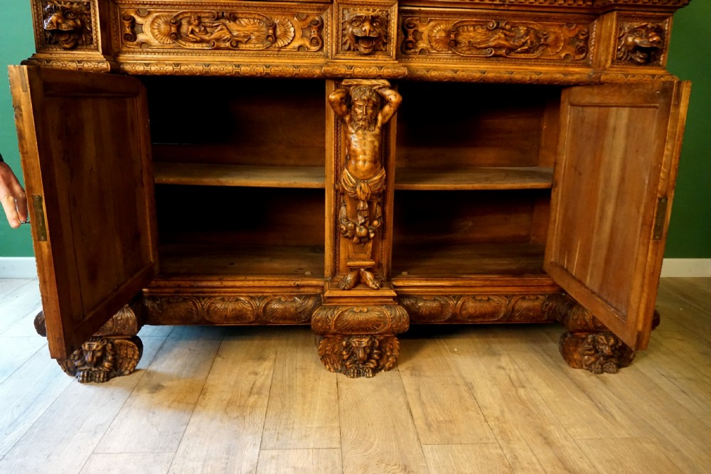 A two-tier carved wooden buffet featuring detailed relief panels of mythological scenes, carved putti, and supporting caryatid figures. View XIV